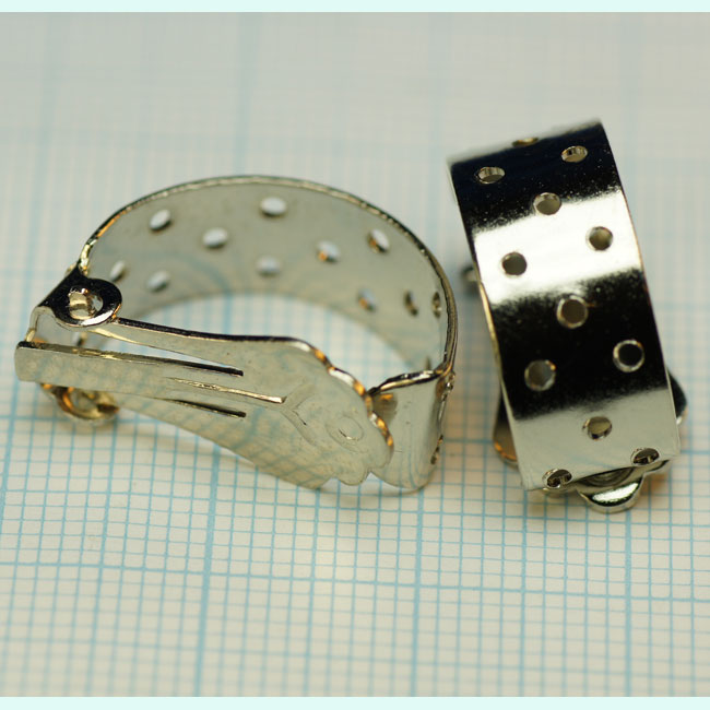 Boucle d'oreille métallique couleur Nickel à clipser. Devant en arc de cercle de +- 17mm de haut agrémenté de 15 trous. Se vend à la pièce. Code: BO004 --- BO Nickel a clipser Devant a trous---