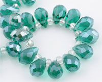 Perle de verre cristal, Goutte avec facettes et éclat. Dimension: +-14x8mm. Percée dans le sens de la largeur côté pointe. Couleur: Vert Émeraude Code: D09225 --- Goutte avec facettes +-14x8mm. Vert Emeraude---