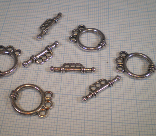 Fermoir 3 rangs en 2 parties. (Rond + barre). Diamètre: +- 18mm. Épaisseur: +- 3,5mm. Trous: +- 2mm. La barre: Longueur: +- 20mm. Largeur: +- 6mm. Épaisseur: +- 3mm. Trous: +- 1,7mm. Couleur: Argent antique Code: LF10795Y --- Fermoir 3 rangs. 2Pcs. Argent Vx.---