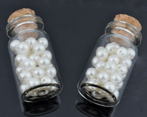 Petite bouteille en verre de +- 42 x 21mm. avec bouchon et remplie de +- 30 perles en matière synthétique de +- 8mm. de couleur crème, marron. Code: D11342 --- Fiole avec perles Crème---