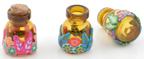 Bouteille de verre pour parfum ou autre liqueide. Fiole décorée avec fleurs et feuilles d'argile de fimo et avec bouchon. Dimension: +- 25x17mm. Multicouleur. Code: D12609 --- Bouteille decoree fleurs 25x17mm.---
